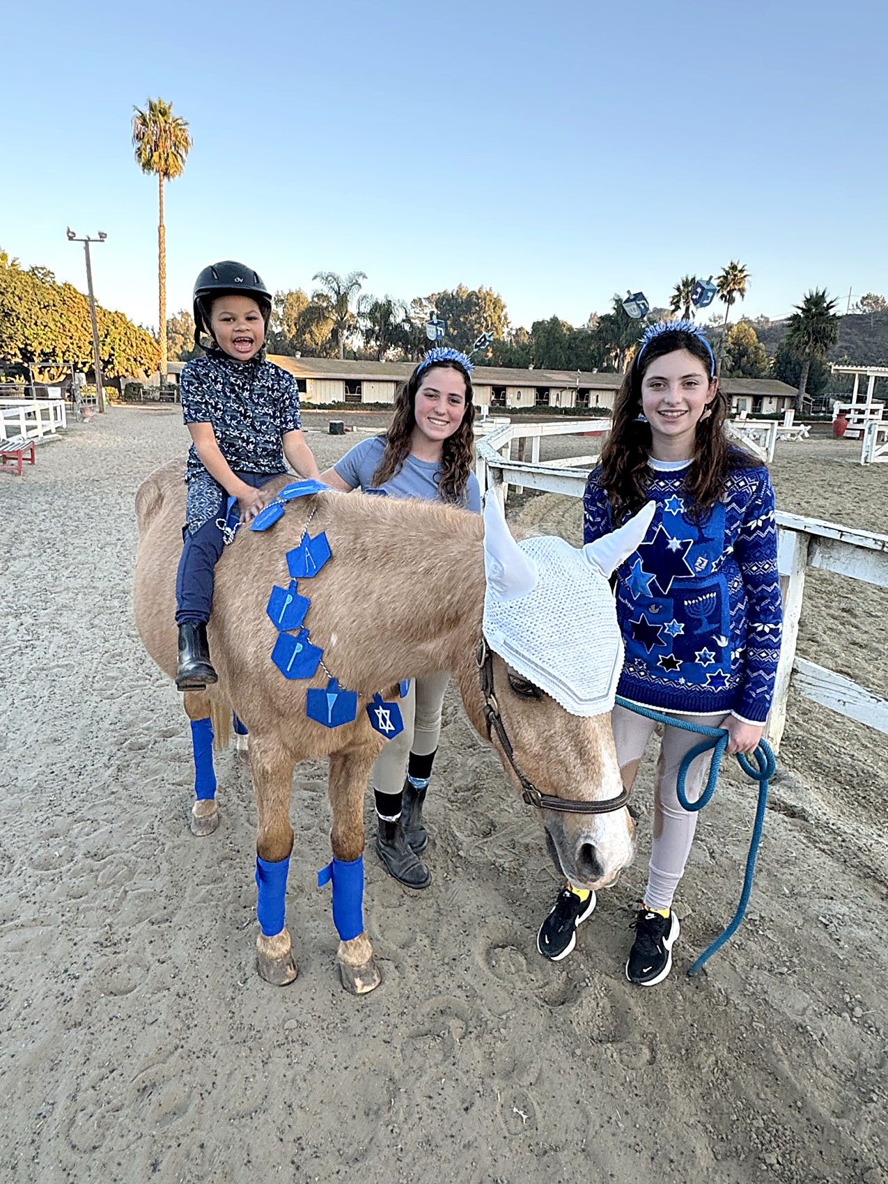 A young rider on Melody with two teen volunteers alongside